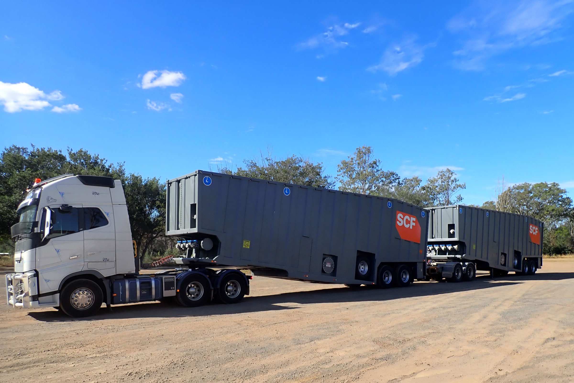 Two SCF Wheeled Bulk Liquid Tanks connected to a truck, in transit to a remote location.